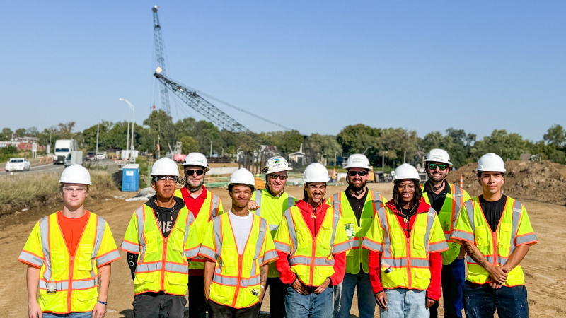 Group of students in safety gear pose at construction site