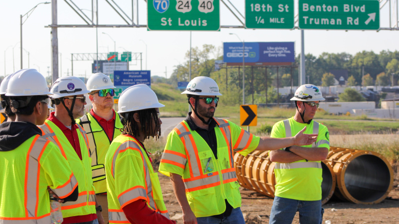 Students tour construction site with highway signs in the background