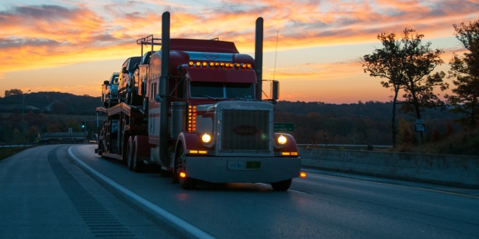 a semi truck drives under a sunset