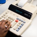 a hand typing on a calculator