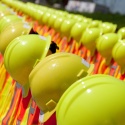 Rows of hardhats lined up on delineaters with safety vests