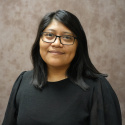 Headshot of a woman with a dark shirt and a brown background