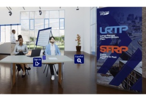 Two people sitting at a table welcoming guests into a room with display boards.