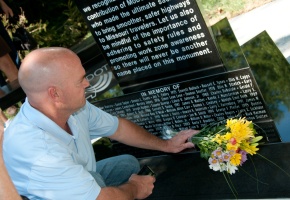 a man lays flowers at the memorial