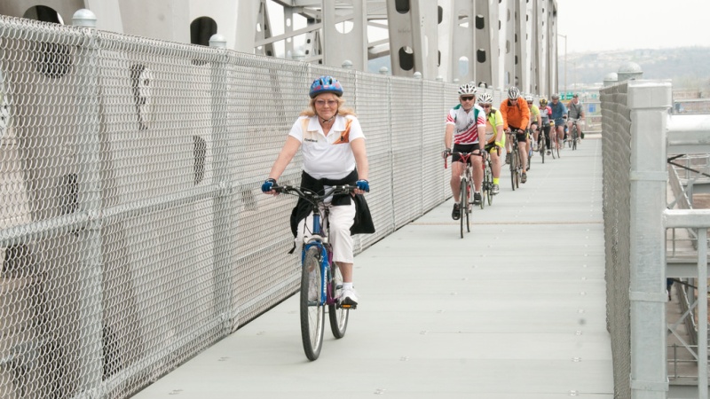 Person riding bicycle on bridge bike path