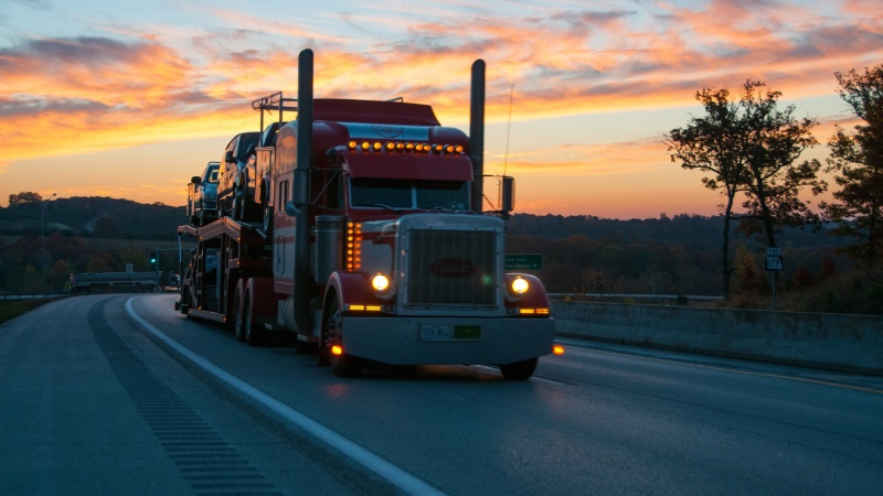 a semi truck drives under a sunset