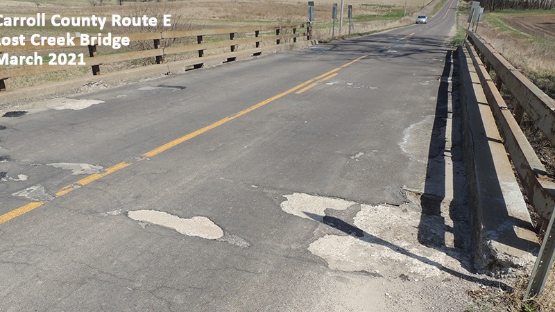 Photo showing the substandard bridge rails and the deteriorating asphalt surface of the Carroll County Route E Lost Creek Bridge