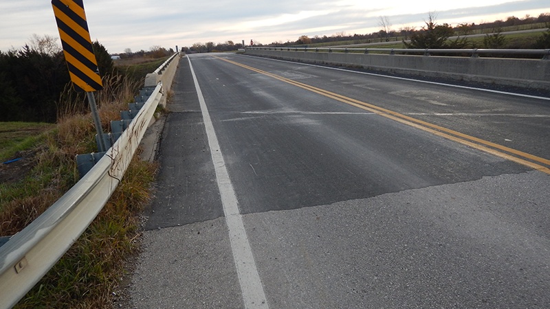 A photo taken just off the end of the Caldwell County Route 116 bridge over the UP Railroad showing the deteriorating driving surface and a bridge joint