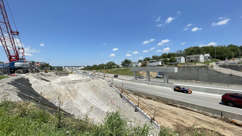 Bridge under construction over active interstate with crane and bridge columns and walls