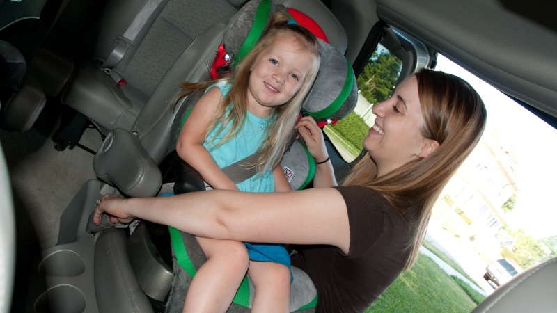 a woman secures a girl's booster seat