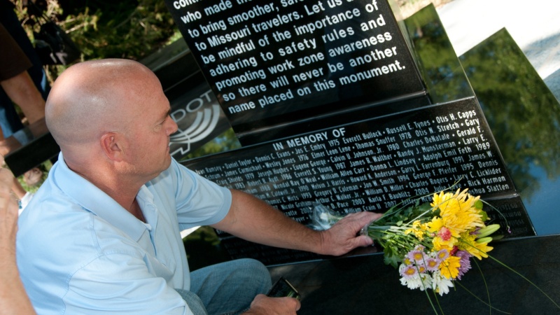 a man lays flowers at the memorial